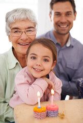 Gran makes the best cupcakes. Portrait of a happy three-generational family celebrating a birthday at home.