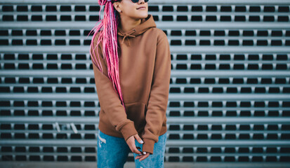 City portrait of handsome hipster girl with colored afro braids wearing brown blank hoodie or hoody...
