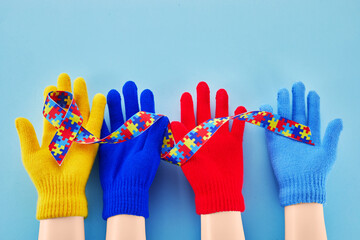 Hands holding puzzle ribbon for World Autism Awareness Day.