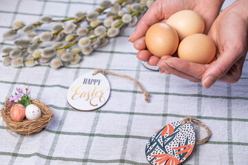 Female hands with chicken  easter eggs and willow branches on background with space for text. Easter background. Easter concept.  Christian religious Easter holiday.
