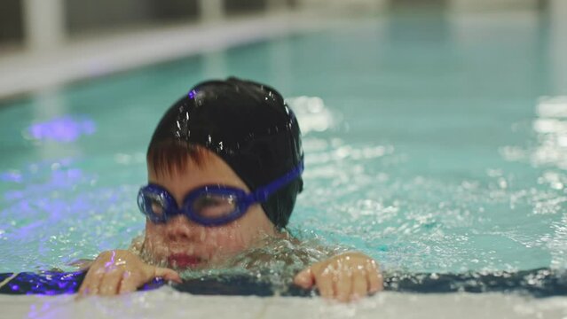 little preschooler boy in pool training child learning to breathe under water dive in swimming class. Male kid 4 years old in swimming cap goggles holding swimming pool side trains dive hold breath 