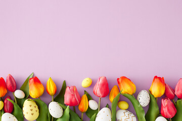Easter celebration concept. Flat lay photo of red tulips with white yellow easter eggs on pastel lilac background with copyspace