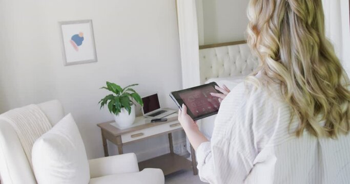 Caucasian plus size woman using tablet with smart home interface in slow motion