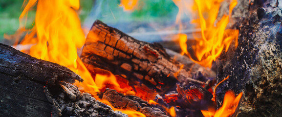 Smoldered logs burned in vivid fire close up. Atmospheric background with orange flame of campfire....