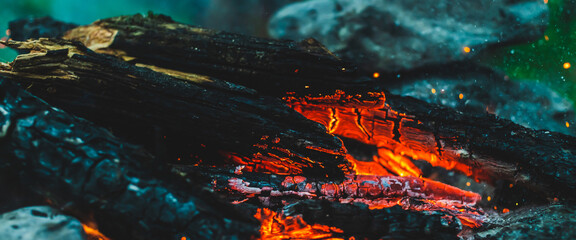 Vivid smoldered firewoods burned in fire close-up. Atmospheric warm background with orange flame of...