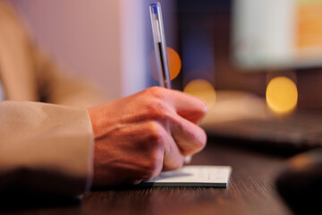 Fototapeta premium Businesswoman writing company profit progress on stickey notes, working late at night in startup office. Executive manager planning marketing strategy, analyzing financial graphs report. Close up