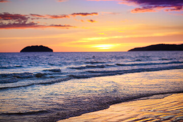 Sunset at tropical beach. Ocean waves by sunrise.