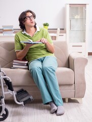 Obraz premium Young male student in wheelchair at home
