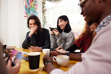 A company of young people in a cafe, have fun, drink coffee, have fun browsing social networks with a cheerful company, modern young people with laptops and smartphones