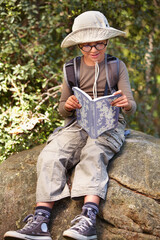 What will I discover today. a young kid reading a book outdoors.