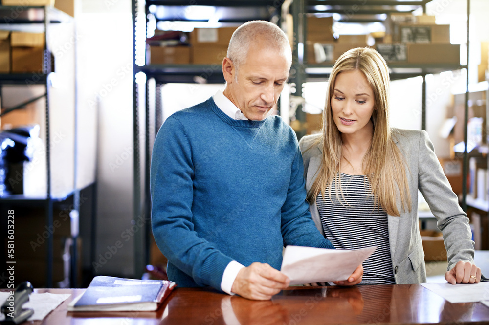 Poster lets check the status of this order. a two managers looking through paperwork on the warehouse floor