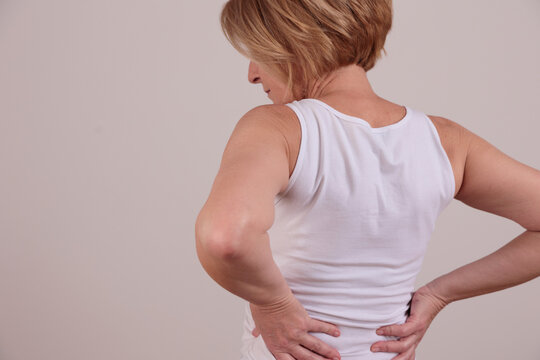 Mature woman suffering from low back pain.Chiropractic, Osteopathy, Physiotherapy concept.