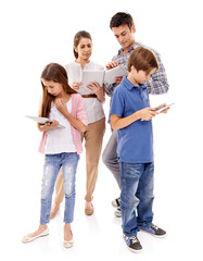 Obraz premium Immersed in the online world. A family of four all using tablets while standing together.