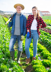 Portrait of farmer couple woman and man with hoe and straw hat standing in a farm