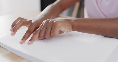 Midsection of african american girl reading braille, slow motion