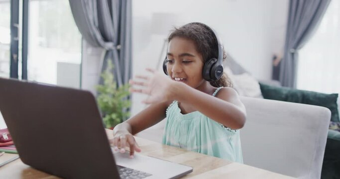 African american girl sitting at table, using laptop for online lesson, slow motion