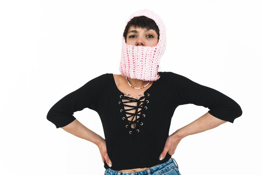 Medium shot of a woman posing with her zhands on her hips and wearing a pink balaclava. High quality photo