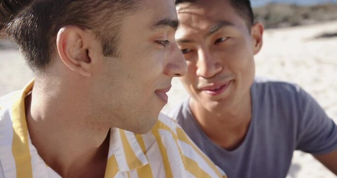 Happy diverse gay male couple embracing at beach, slow motion