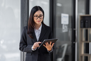 Portrait of Young business asian woman using tablet, standing in office.
