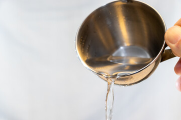 金属製のカップを傾けて液体を注ぐ
