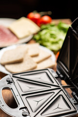 Cooking sandwiches in a sandwich maker. Different ingredients - bread, cheese, vegetables on a...