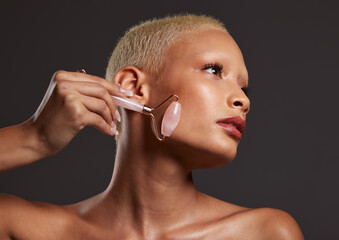 Woman, skincare and roller in beauty for facial cosmetic treatment against gray studio background....