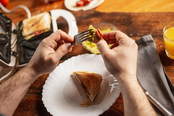 unrecognizable man eats toast with guacamole. Breakfast time. The man's hands are holding a toast.