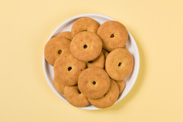 Group of tasty cookies or biscuit in plate on yellow background.