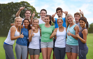 Were committed to fitness. A happy group of young people smiling at the camera while standing on a sportsfield.