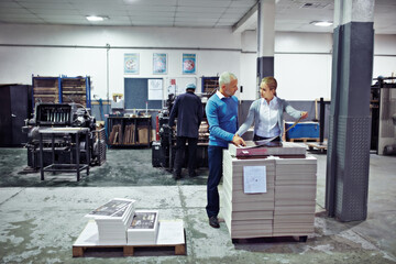 Discussing improvements to production. two colleagues inspecting inventory in a printing factory.