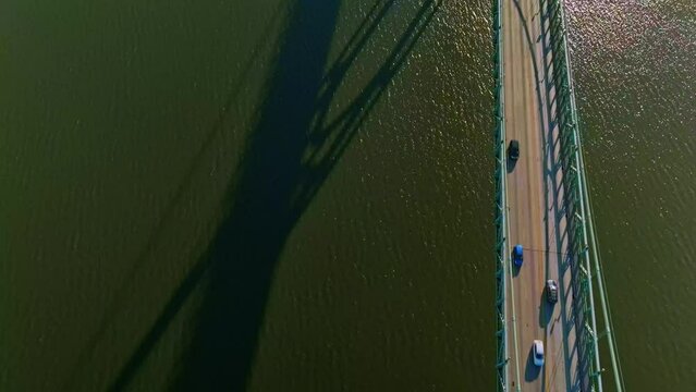 Aerial view-slowly flying forward from middle of the river-camera slow tilt-up revealing early morning sun reflecting off the water, dual gothic style towers of St Johns Bridge in Portland Oregon