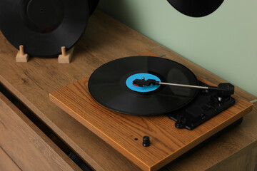 Vinyl record player on wooden chest of drawer indoors