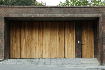 Brick wall with wooden entrance door and gates. Exterior design