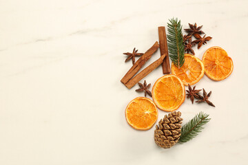 Dry orange slices, cinnamon sticks, fir branches and anise stars on white marble table, flat lay with space for text