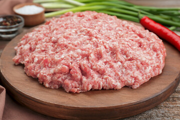 Board with raw fresh minced meat on wooden table, closeup