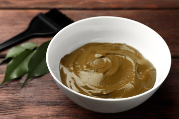 Bowl of henna cream on wooden table, closeup. Natural hair coloring