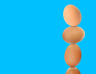 Stacked fresh chicken eggs against light blue background. Space for text
