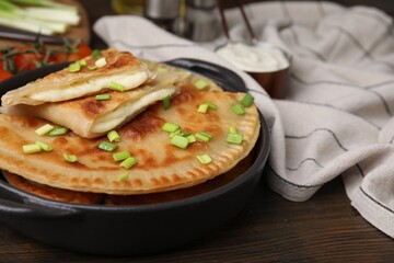 Delicious fried chebureki with cheese and green onion on wooden table, space for text