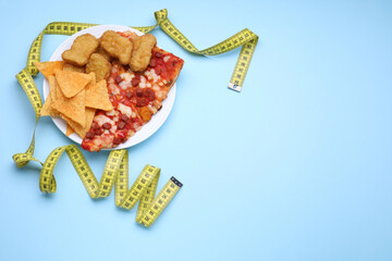 Chips, chicken nuggets, pizza and measuring tape on light blue background, flat lay and space for text. Diet concept