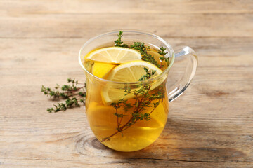 Aromatic herbal tea with thyme and lemon on wooden table