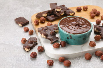Bowl with tasty paste, chocolate pieces and nuts on wooden board, closeup