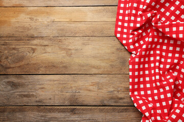 Obraz premium Checkered tablecloth on wooden table, top view. Space for text