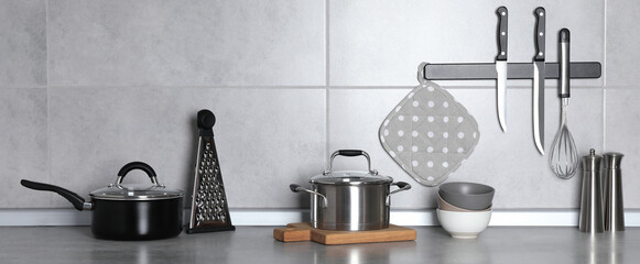 Set of cooking utensils and cookware on grey countertop in kitchen, banner design