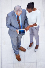 Managing projects has never been easier. High angle shot of two business colleagues standing with a digital tablet.