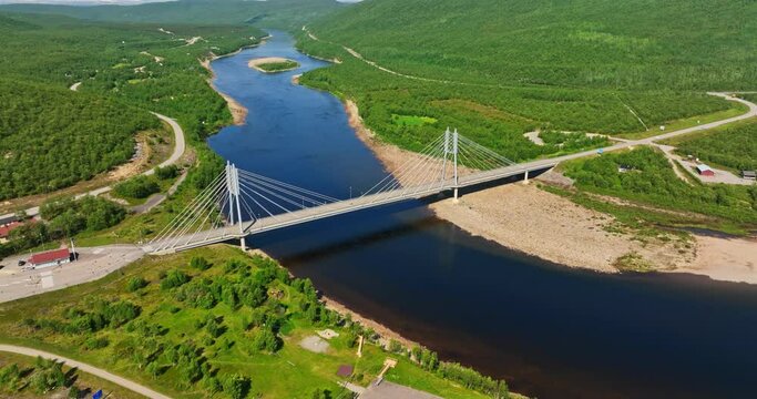 Aerial view away from the Sami Bridge, summer in sunny Utsjoki, Finland - reverse, tilt, drone shot