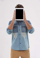 The face of new tech. a young man holding a blank digital tablet in front of his face.