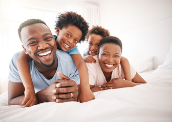 Happy, laughing and portrait of a black family on a bed for playing, quality time and comfort. Bonding, love and African children with parents in bedroom for happiness and relaxation in the morning