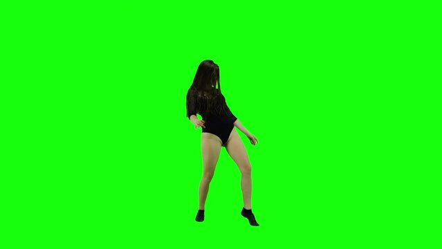 Carefree young happy woman listening to music and dancing alone on green screen background