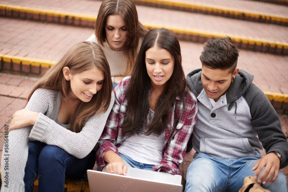 Poster Working on their latest assignment. High angle of a group of university students using a laptop on campus.