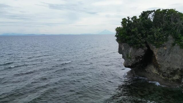 Breathtaking, Establishing Drone shot of large rock in vast, turquoise ocean resembling face of Jesus. Talisoy, Catanduanes.